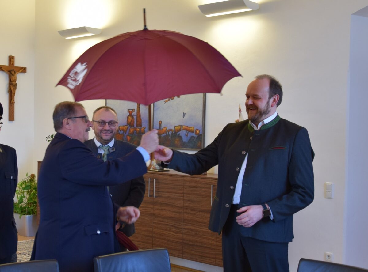 Landrat Andreas Meier und Bürgermeister Markus Bauriedl freuen sich über den
vom Feuerwehr-Vorsitzenden Hermann Gilch übergebenen Schirm. Foto: Marcel Weidner (Landratsamt)
