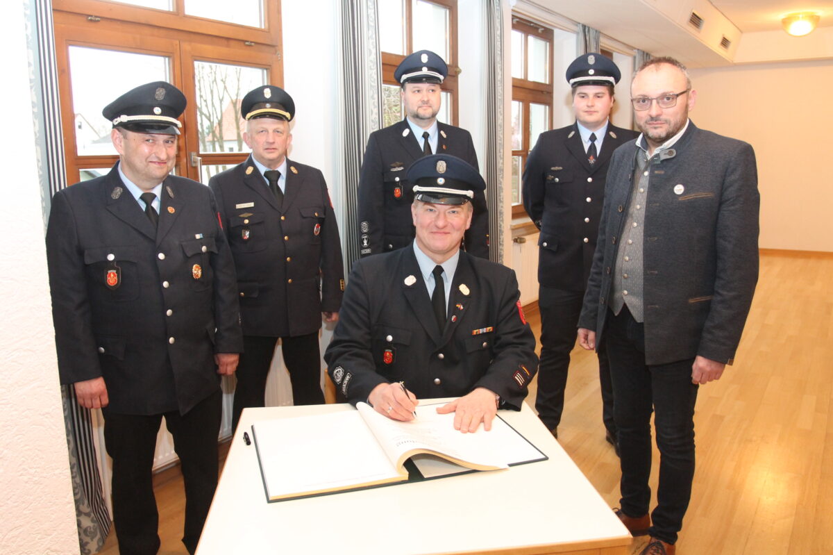 Markus Schwarz (sitzend) und Hans-Peter Müller (links) tragen sich in das
Goldene Buch ein. Glückwünsche gibt es von Bürgermeister Markus Bauriedl,
Maximilian Fuchs, Johann Dierl und Kreisbrandinspektor Martin Weig (von
rechts). Foto: Josef Pilfusek