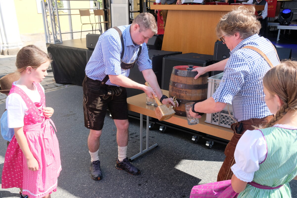 Gut vorbereitet zeigte sich Commander John Steaheli beim Anzapfen des ersten Festbier-Fasses. Es
assistierte Stadtverbandsvorsitzender Michael König. Neugierig beobachten die Kinder des
Kommandanten die Zeremonie. Foto: 
Robert Dotzauer